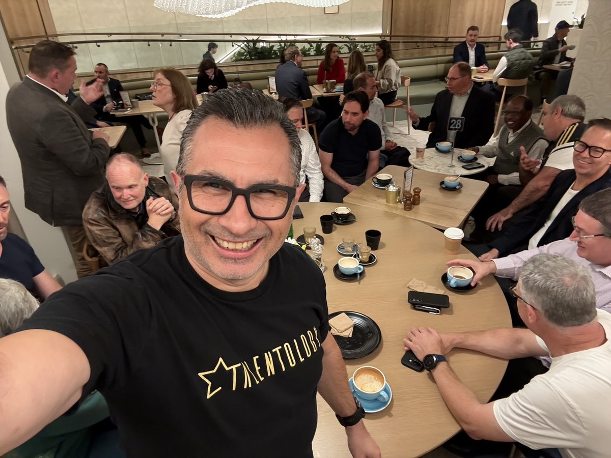 Trevor Churchley taking a selfie with a large group of job seekers around tables at the Job Seeker Cafe in Sydney